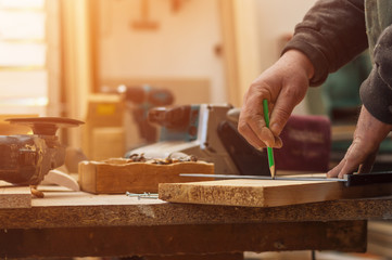 Craftsman measuring wooden plank with ruler and pen, lens flare