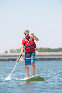 man enjoying a ride on the lake with paddleboard