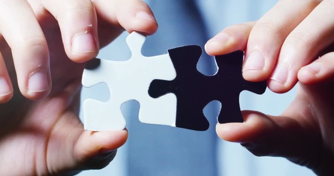 A creative completes the black or white light puzzle putting the last missing piece. Concept: cooperation, teamwork, creativity, and access solution.