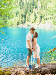 Kissing couple and mountain blue lake. Love story on nature. Sun light