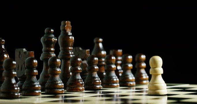 Macro shot of chess, in which a white piece tackles all the black pawns. Concept: challenge, one against all, team success sport.
