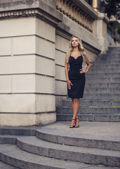 Elegant young woman standing on beautiful stairs outdoors