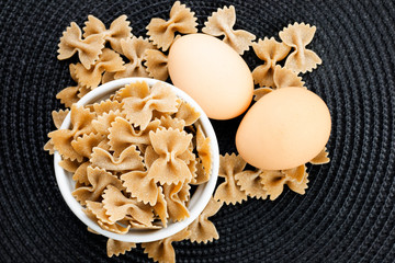 Organic Farfalle pasta and eggs on black placemat