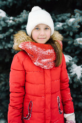 portrait of a girl in a red jacket, near the green tree on the street