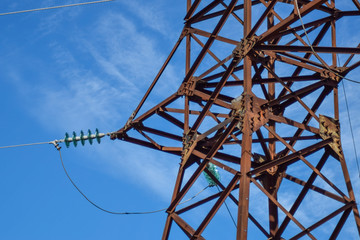 Supports high-voltage power lines against the blue sky with clouds. Electrical industry