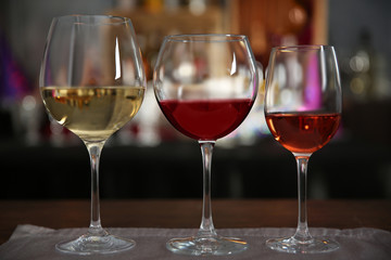 Three glasses with tasty wine in bar on bright background