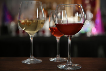 Three glasses with tasty wine in bar on bright background