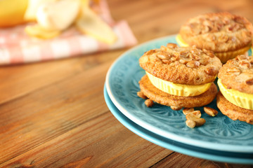 Plate with delicious lemon ice cream cookie sandwiches on wooden table