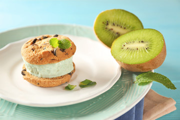 Plate with delicious ice cream cookie sandwich and kiwi, closeup