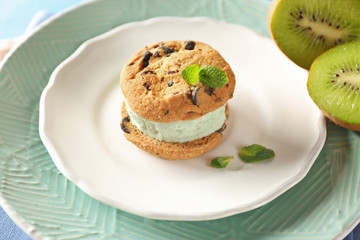 Plate with delicious ice cream cookie sandwich and kiwi, closeup