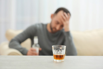 Glass with whisky on table and blurred man on background