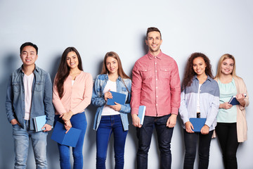 Obraz premium Group of people with books standing near light wall