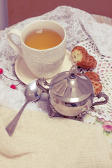 Happy Valentines day tea time or love party. White cup of green tea with cakes raisin chocolate cookies in shabby chic elegant traditional interior, lace napkin with pink flowers. Cookie heart shape.
