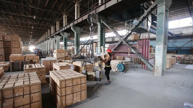 woman Factory worker in helmet transporting packing firebricks with workshop rail mounted gantry crane