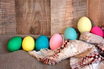 Easter colored eggs with bow against natural wooden textured background on linen fabric. Rustic vintage country style. Happy easter background concept.