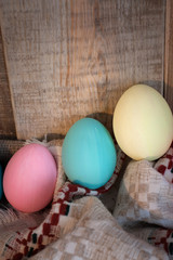 Easter colored eggs with bow against natural wooden textured background on linen fabric. Rustic vintage country style. Happy easter background concept.