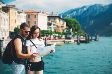 Smiling couple with a map at Lake Garda, Italy - obrazy, fototapety, plakaty
