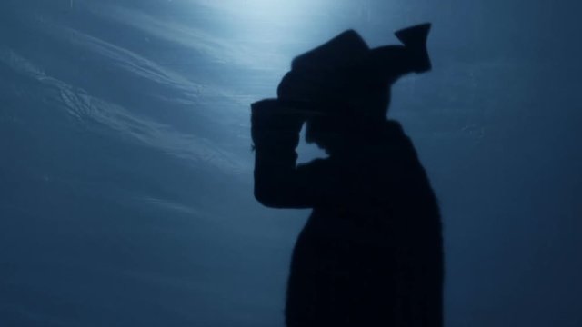 Malicious dwarf silhouette in hat cutting something with sharp axe, nightmare