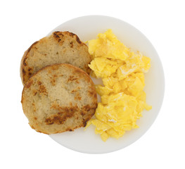 Top view of a fried English muffin with scrambled eggs on a plate isolated on a white background.