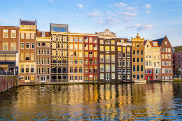 Traditional old buildings and boats at sunset in Amsterdam, Netherlands.