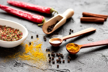 spices in wooden spoon on dark background