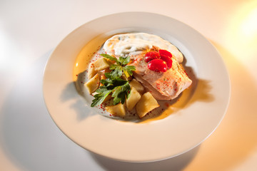 Fish on a plate with white sauce with potatoes and peppers