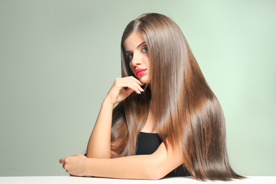 Young woman with healthy hair on color background