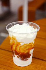 Plastic cup of delicious cool dessert on wooden table