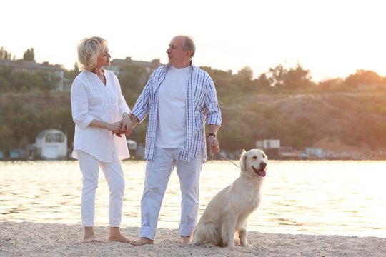 Senior couple and big dog on riverside
