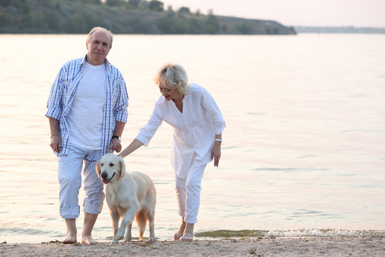 Senior couple and big dog walking on riverside