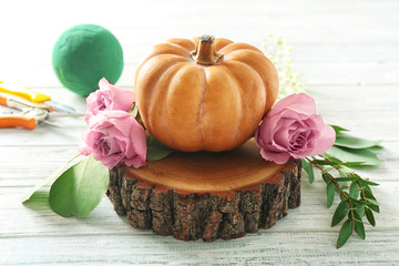 Pumpkin and fresh flowers on white wooden table