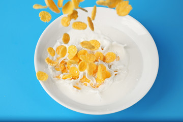 Corn flakes with milk in bowl on blue background
