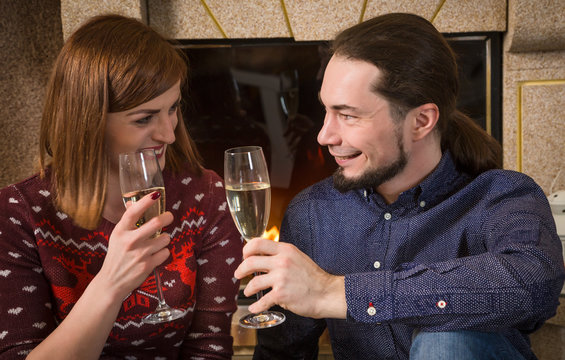 Couple with champagne together near fireplace