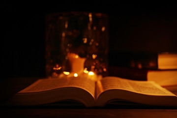 Bible and burning candles on wooden table