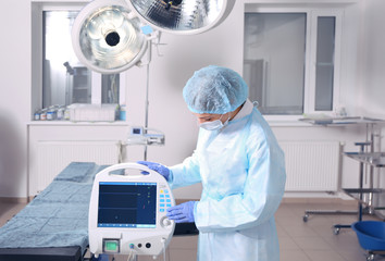 Young doctor adjusting equipment in operating room of modern clinic