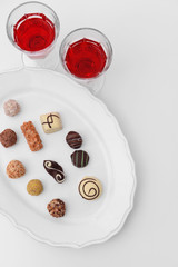 Delicious chocolate candies and wine on white background
