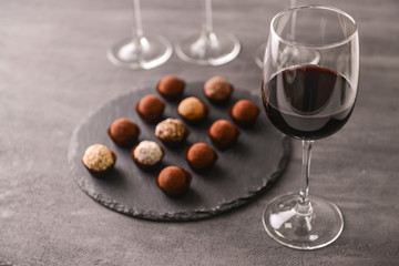Delicious chocolate truffles and red wine on grey background