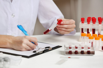 Woman working with blood samples in laboratory, closeup