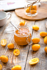 kumquat on plate and jam in jar at wooden table