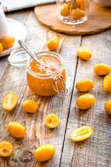 kumquat on plate and jam in jar at wooden table