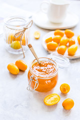 kumquat on plate and jam in jar at gray background