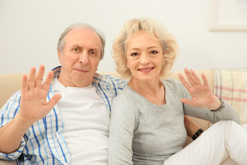 Happy senior couple sitting on sofa at home