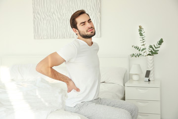 Handsome man feeling back pain at home