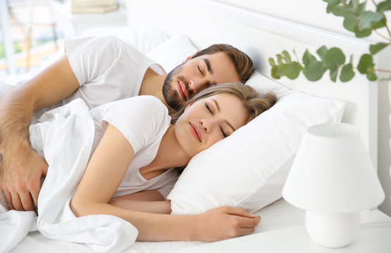 Young cute couple sleeping together in bed