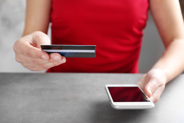Woman holding credit card and using smart phone