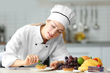 Female chef decorating fruit tartlet in kitchen