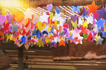 Colorful candle stars and hearts hanging and wooden abstract background