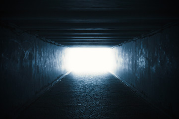 Empty dark underpass tunnel with light in the end, soft focus