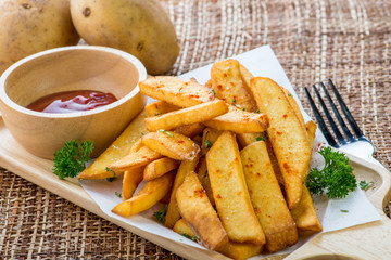 Tasty french fries on cutting board with ketchup, on wooden table background