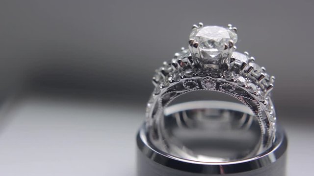Bride's engagement ring inside grooms wedding band, close up rack focus